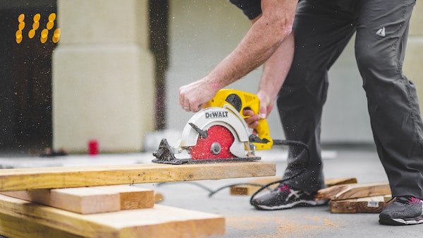 man in black sweatpants using a circular saw