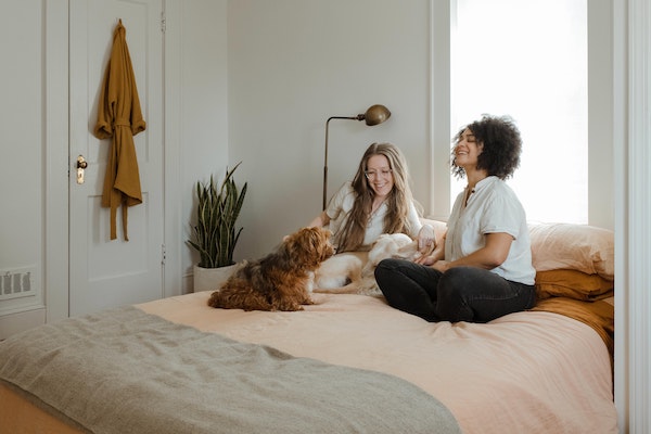 two women sitting on bed with a dog